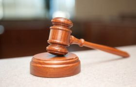 En træhammer placeret på et bord i en retssal.