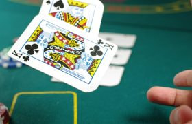 To spillekort bliver kastet på et spillebord med pokerchips.