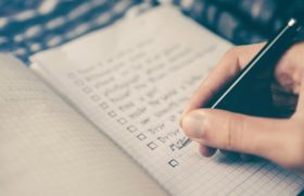 Skriver noter I notesbog