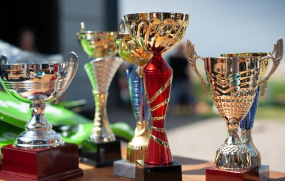 Fem trofæer placeret på bord.