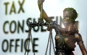 Kvindelig statue med vægt foran skilt.