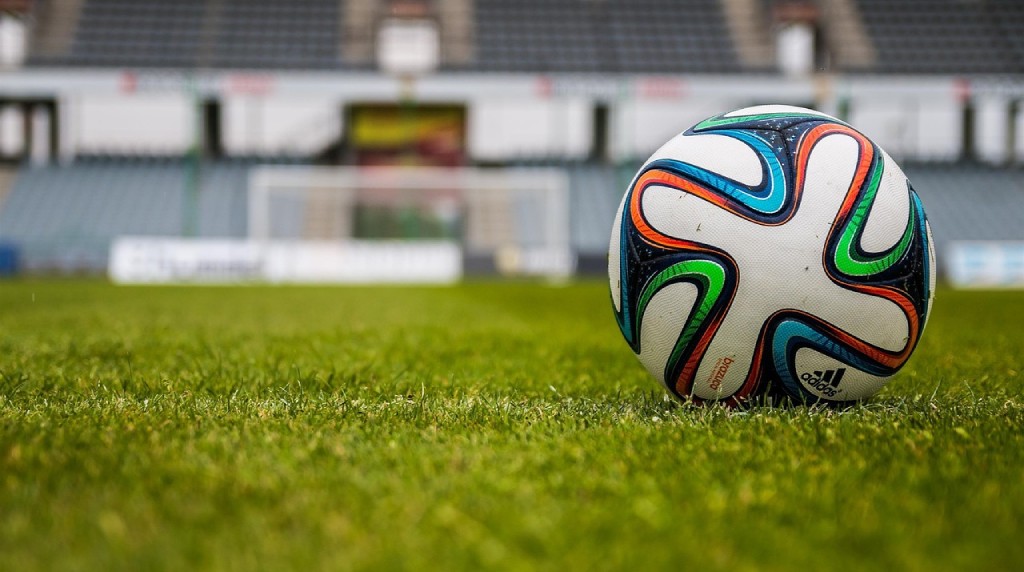 Fodbold ligger på græs i stadium