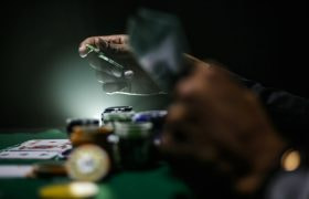 Pokerbord med jetoner og hænder med kort