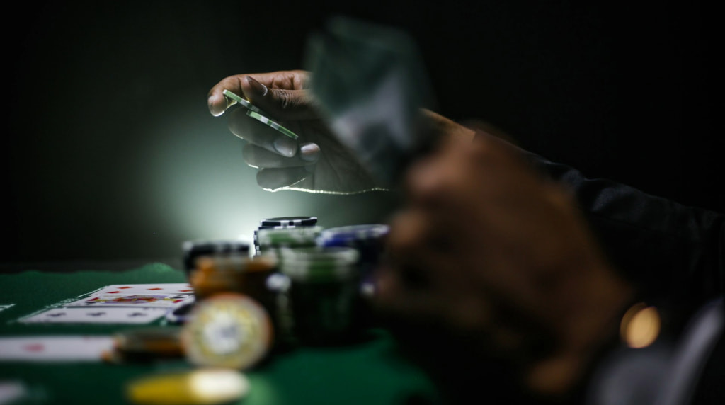Pokerbord med jetoner og hænder med kort