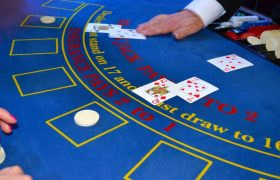 Tavolo di blackjack con croupier e giocatore che punta.