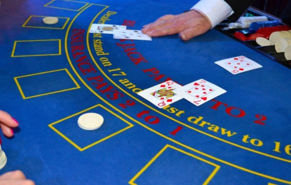 Tavolo di blackjack con croupier e giocatore che punta.