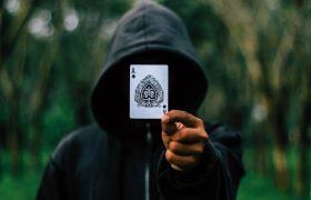 Persona incappucciata mostra un asso di picche