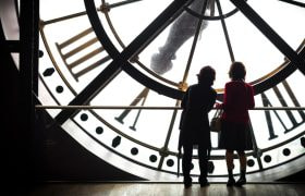 Due persone osservano un grande orologio monumentale illuminato.