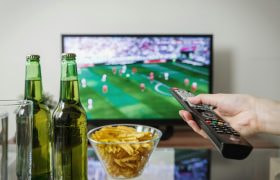 Partita in TV con birra, patatine e telecomando.