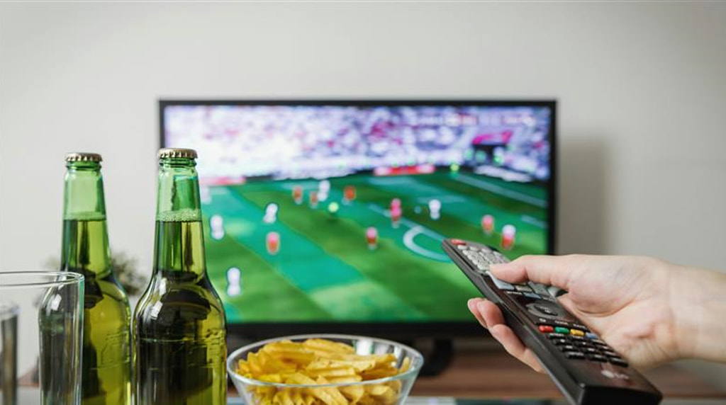Partita in TV con birra, patatine e telecomando.