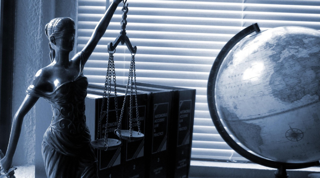 Statua della giustizia accanto a un mappamondo e libri legali.