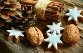 Pigne, cannella e biscotti a stella su legno rustico.