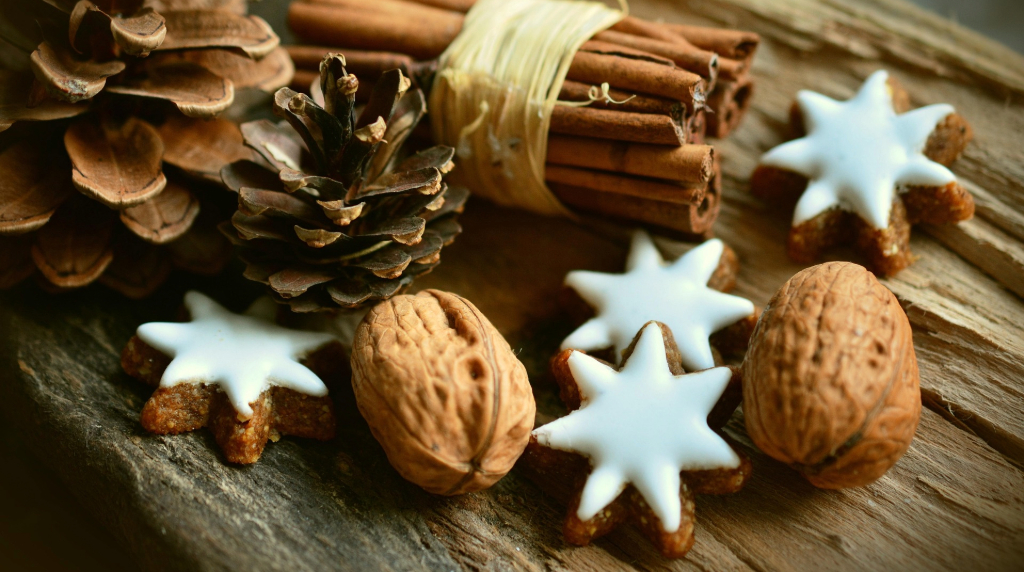Pigne, cannella e biscotti a stella su legno rustico.