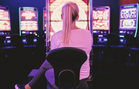 Donna di spalle davanti a file di slot illuminate
