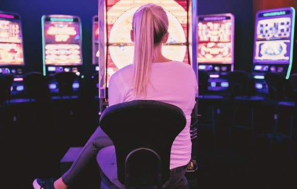 Donna di spalle davanti a file di slot illuminate