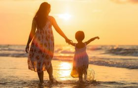 Donna e bambina al tramonto sulla spiaggia.