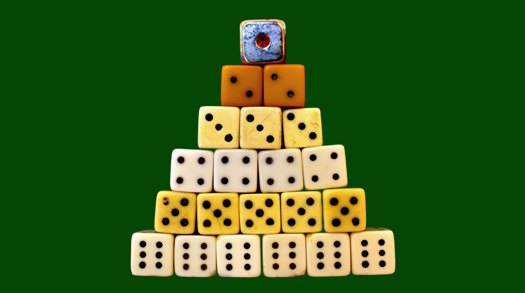 Piramide di dadi impilati su sfondo verde uniforme