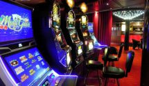 Sala casinò con slot machine illuminate e sedute in fila