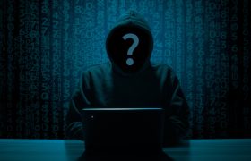 Figura incappucciata davanti al laptop tra codici digitali