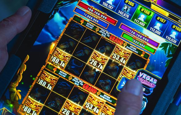 Handen van iemand die een online gokkast speelt op een tablet