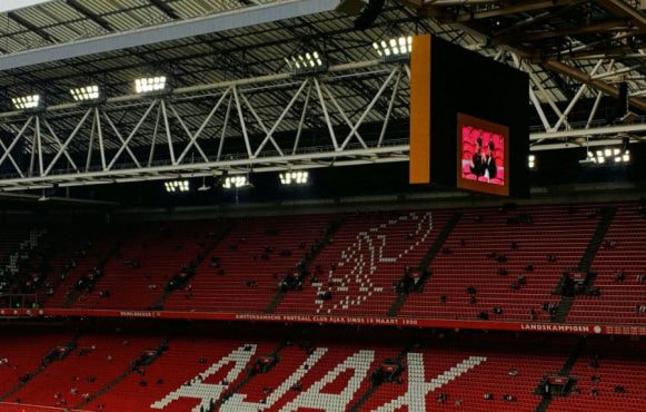 Vrijwel leeg Ajax stadion, het Ajax logo is te zien op de rode tribune