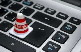 Toetsenbord met daarop een rood/witte pylon met het woord “caution”