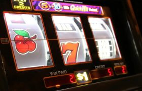 Close-up van een gokautomaat, met de symbolen kersen en de “lucky 7”