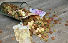 Glas dat vol zit met geld, omgevallen is op een houten vloer. Inclusief een briefje van 500 euro.