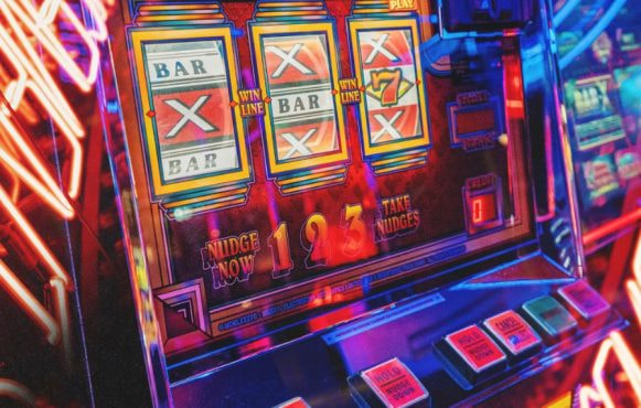 Close-up van een gokautomaat, omgeven door neonverlichting en ontzettend veel kleuren.