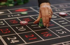 Vrouwenhand die casino chips plaatst op een casinotafel met speelkaarten.