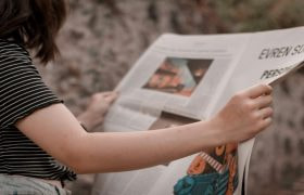 Vrouw leest een krant in de buitenlucht.