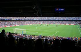 Zicht op een voetbalwedstrijd vanuit de tribune van een vol stadion