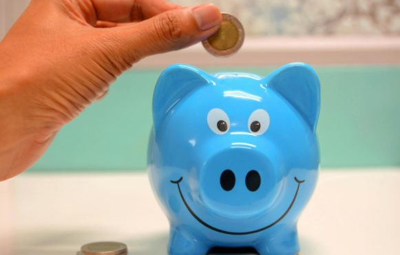 Blauw lachend spaarvarken en hand met een euromunt