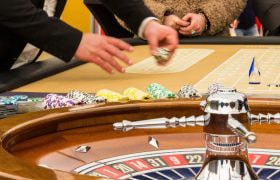 Mensen aan roulettetafel en croupier met fiches in zijn hand