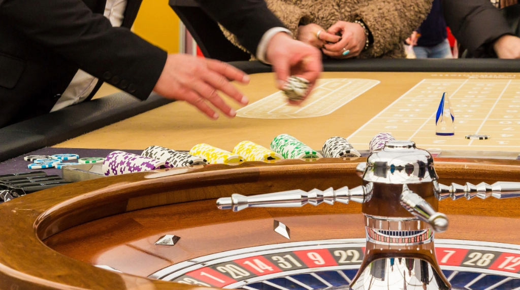 Mensen aan roulettetafel en croupier met fiches in zijn hand
