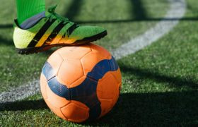 Voetballer heeft voet op oranje bal