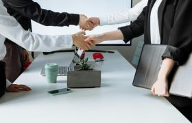 Vier mensen die elkaar de hand schudden in een kantoorruimte