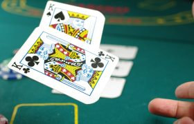 Groene tafel en een hand die twee kaarten (koningen) opgooit