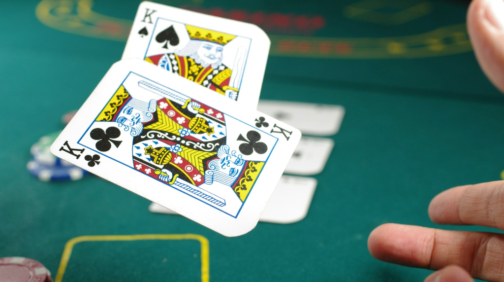Groene tafel en een hand die twee kaarten (koningen) opgooit