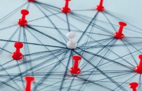 Prikbord met meerdere rode en een witte punaise, verbonden met touwtjes