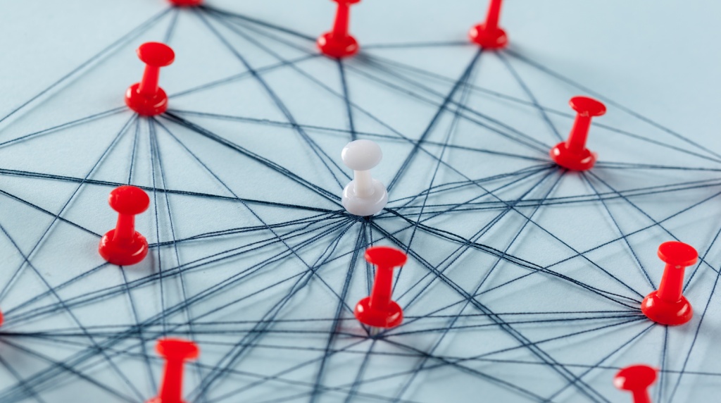 Prikbord met meerdere rode en een witte punaise, verbonden met touwtjes