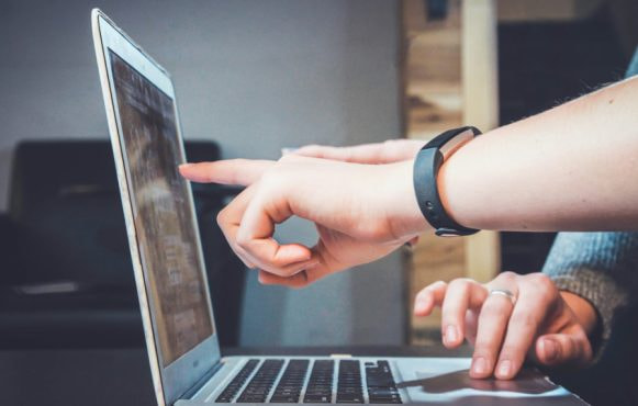 Handen die wijzen naar scherm van een laptop