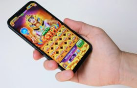 Hand met telefoon, op de telefoon is een gokspel te zien