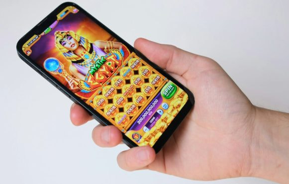 Hand met telefoon, op de telefoon is een gokspel te zien