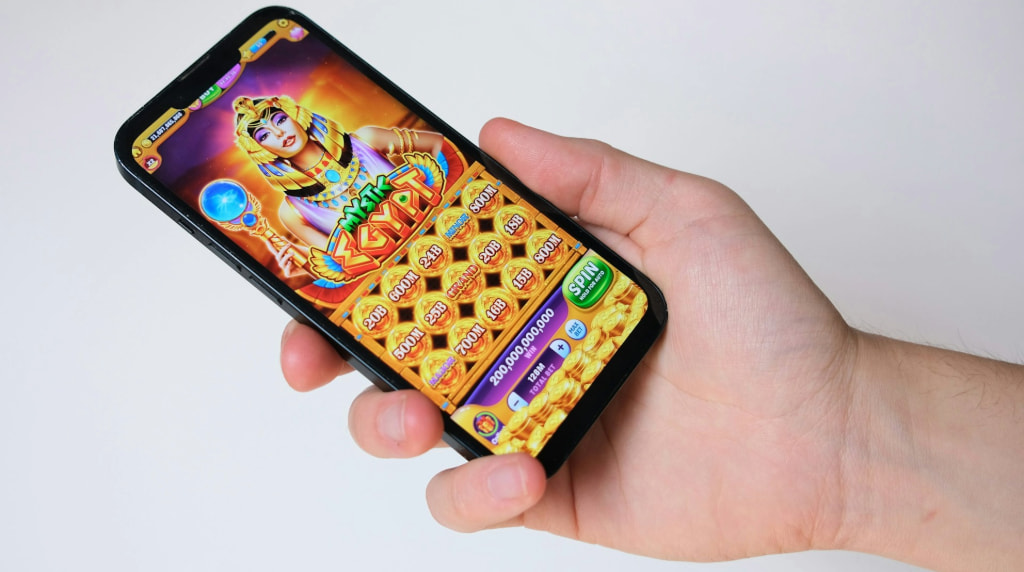 Hand met telefoon, op de telefoon is een gokspel te zien