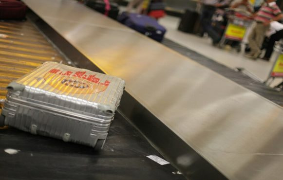 Zilveren koffer op de bagageband van een vliegveld