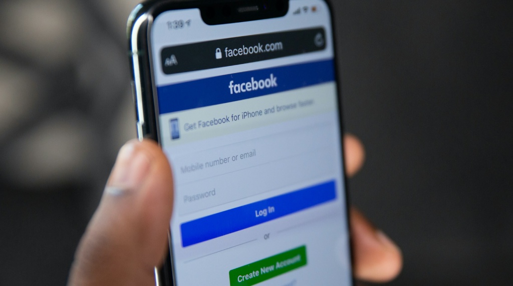 Hand met telefoon, daarop is het inlogscherm te zien van Facebook