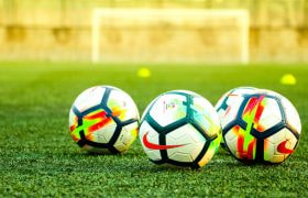 Drie voetballen op een groen voetbalveld