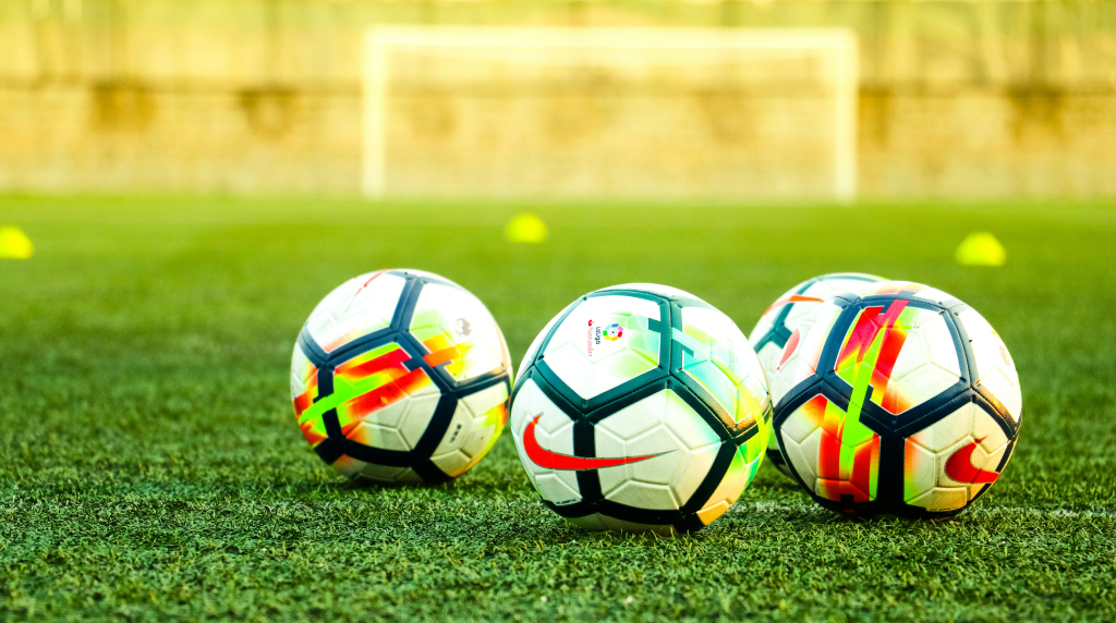 Drie voetballen op een groen voetbalveld