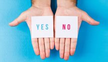 Twee handen met ieder een briefje, op de ene staat Yes en op de andere No